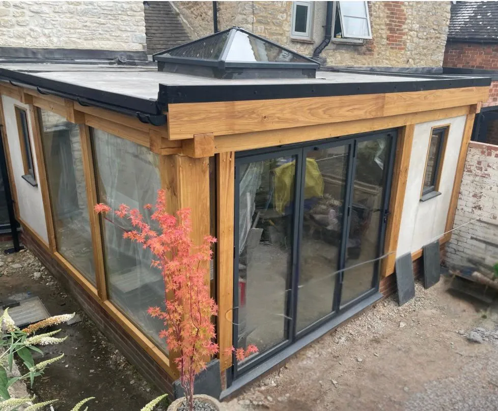 Flat roof oak orangery with a glazed lantern and sliding doors