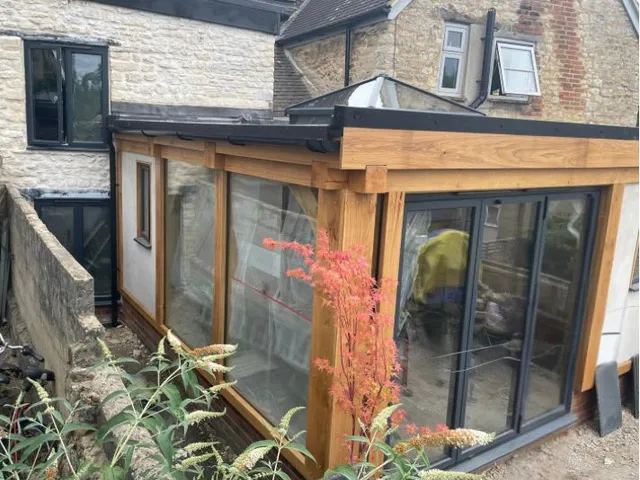 Side of the flat roof oak orangery with glazing between the oak posts