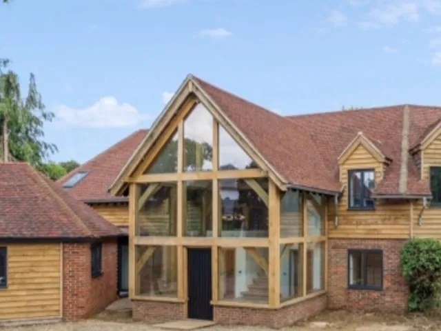 Two-storey glazed oak framed entrance extension on a brick and oak-clad house