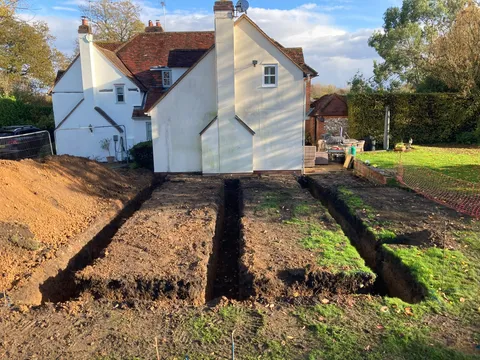 Foundation trenches dug for an extension at the rear of a white house