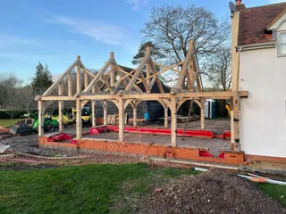 Oak frame and trusses raised on the brick plinth before roofing