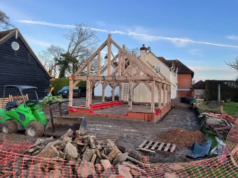 Oak frame raised on its new brick plinth with the loader clearing the site