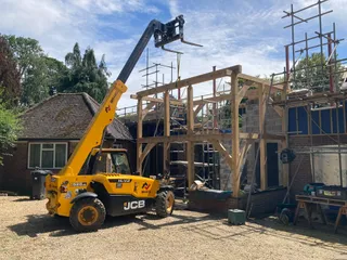 JCB telehandler lifting the two-storey oak frame into place