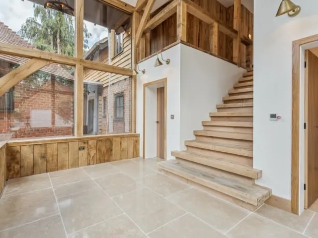 Inside a two-storey oak framed entrance hall with the staircase and oak boarded walls