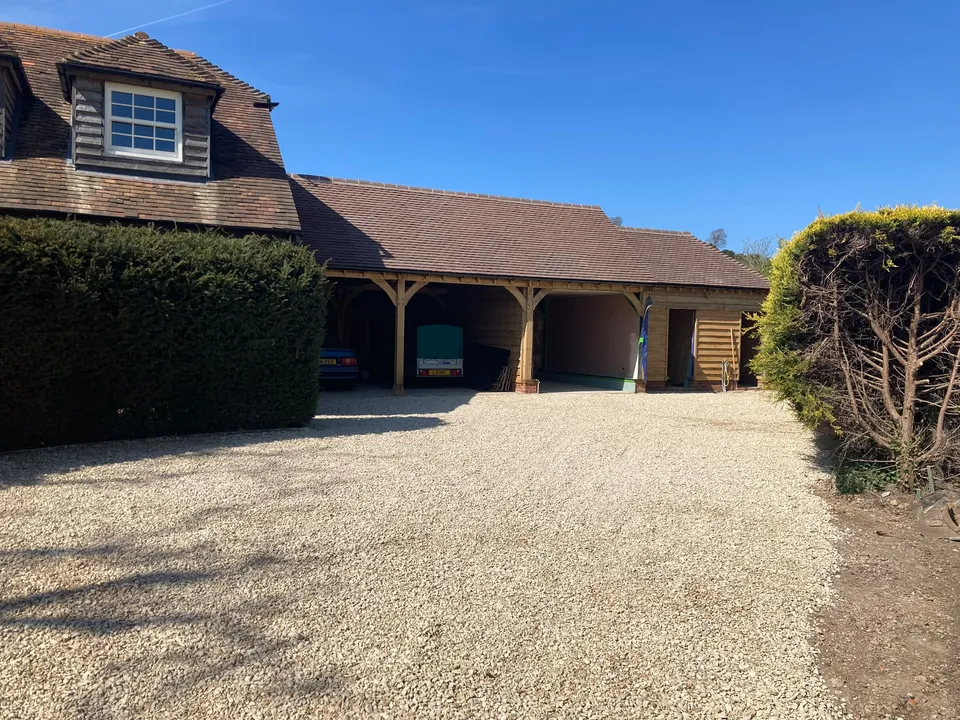 Three bay oak framed garage with a tiled roof and gravel drive