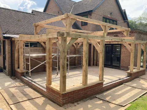 Corner of the oak orangery frame raised on its brick plinth against the house