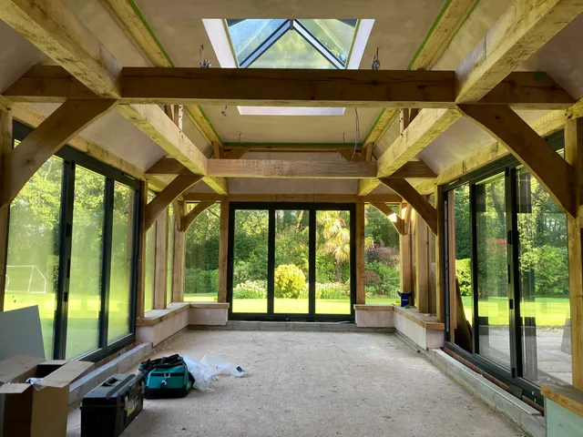 Inside the oak garden room: exposed oak beams, roof lantern and glazed doors to the garden