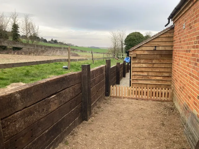Oak sleeper retaining wall beside the garage with a new fence above