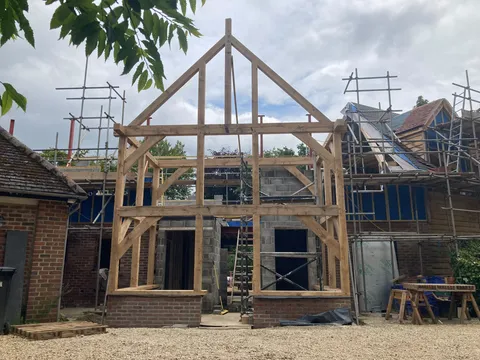 Two-storey oak frame gable raised against the house with scaffolding behind